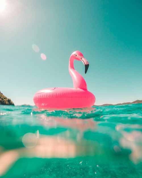 Photo d'une bouée flament rose sur l’eau turquoise prise depuis une villa à Ibiza