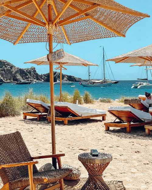Transats et parasols en bord de mer sur une plage ensoleillée d'une location de villa Le Collectionist à Ibiza