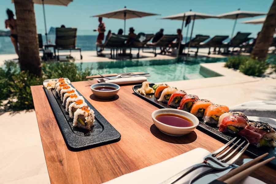 Déjeuner au bord de la piscine avec vue sur la mer et assiettes de sushi colorées, parfait reflet de l’art de vivre à Ibiza (location villa Le Collectionist)