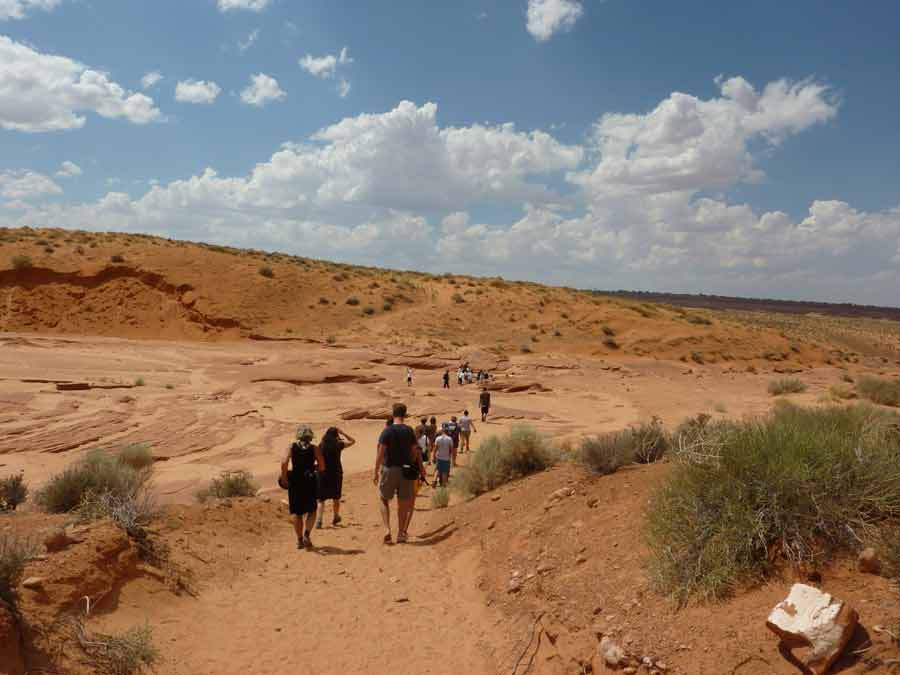 Approche du Lower Antelope Canyon à pied à travers le désert de l’Arizona, visiteurs descendant vers l’entrée du canyon