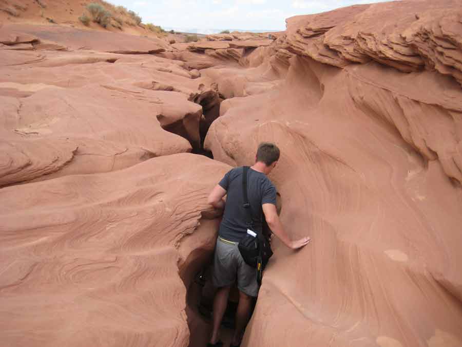 Passage étroit dans le Lower Antelope Canyon, visiteur progressant au cœur d’une faille rocheuse sculptée par l’érosion