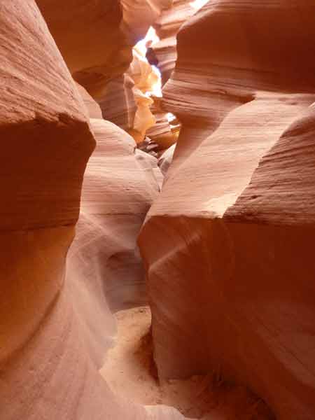 Passage sinueux du Lower Antelope Canyon, couloir étroit aux parois de grès ondulées baignées de lumière naturelle