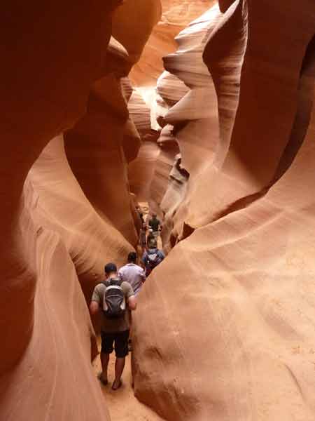 Progression des visiteurs dans le Lower Antelope Canyon, couloir étroit aux parois de grès lisses et ondulées