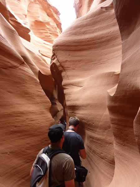 Passage resserré du Lower Antelope Canyon, visiteurs marchant au cœur d’un canyon sinueux aux parois sculptées