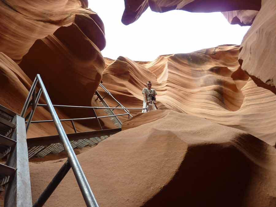 Escalier métallique du Lower Antelope Canyon, visiteur gravissant un passage sableux entouré de parois de grès sculptées par l’érosion