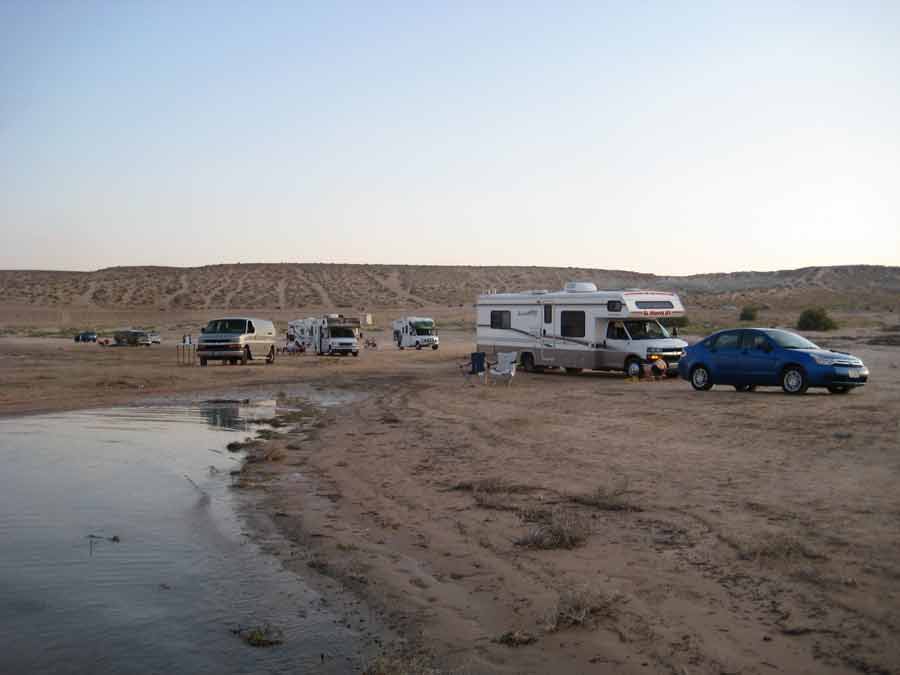 Bord du Lake Powell avec camping-cars et véhicules stationnés près de l’eau, paysage désertique de l’Arizona en fin de journée