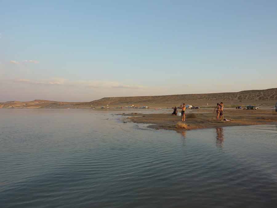 Bord du Lake Powell au coucher du soleil, visiteurs profitant des eaux calmes dans un décor désertique