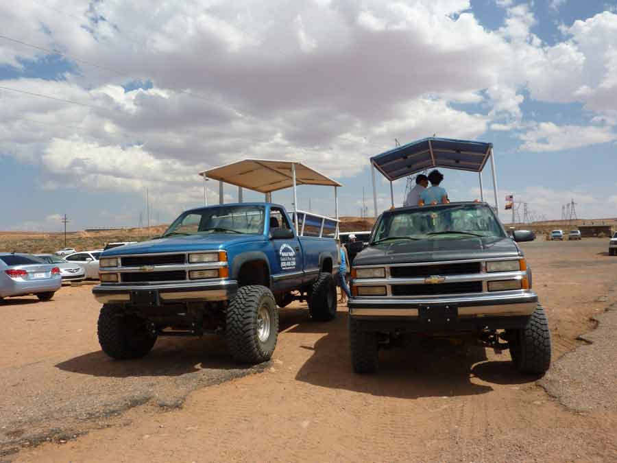 Véhicules tout-terrain utilisés pour accéder à Upper Antelope Canyon, stationnés sur un parking désertique sous un ciel nuageux