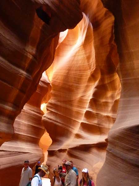 Jeux de lumière à l’intérieur d’Upper Antelope Canyon, parois ondulées de grès et visiteurs progressant dans le canyon