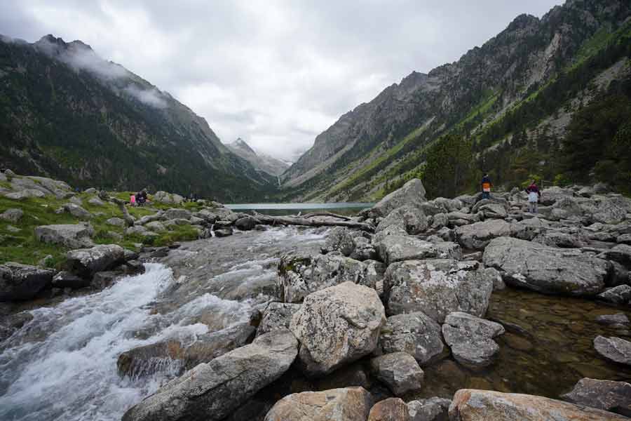 Arrivée au lac de Gaube après la randonnée depuis le pont d’Espagne, avec torrent, rochers et montagnes pyrénéennes sous un ciel couvert