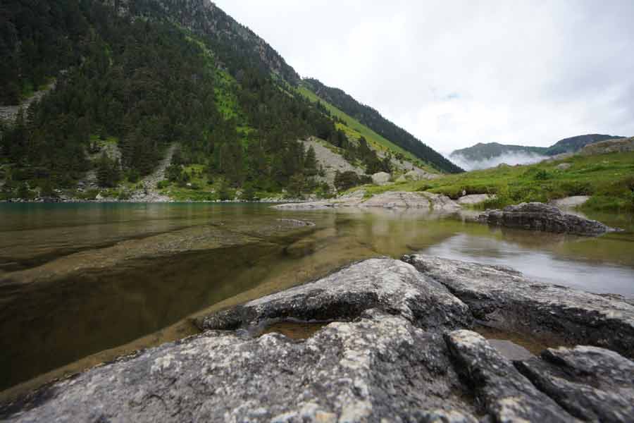 Vue intimiste du lac de Gaube depuis les rochers, ambiance minérale et montagnes pyrénéennes sous un ciel nuageux