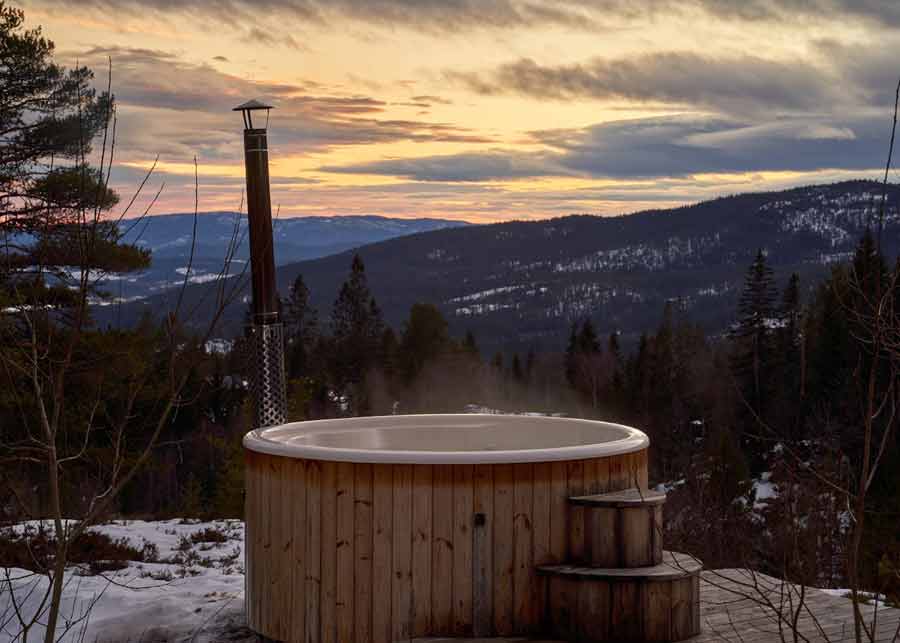 Bain nordique en bois face aux montagnes vosgiennes au coucher du soleil