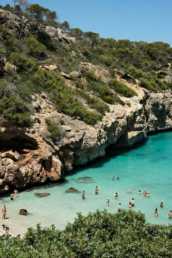 Crique aux eaux turquoise dans les Baléares en Espagne avec des baigneurs profitant d’une plage sauvage lors d’un voyage organisé par Fram