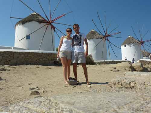 Deux visiteurs posant devant les moulins à vent iconiques de Mykonos par une belle journée ensoleillée