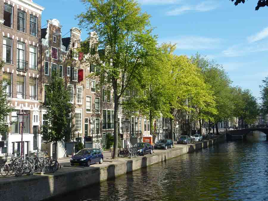 Photo de maisons typiques et d'arbres le long d’un canal d’Amsterdam dans le quartier Jordaan lors de notre visite d'Amsterdam