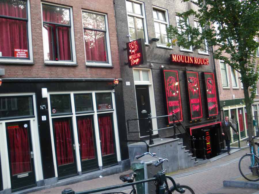 Devanture du quartier rouge à Amsterdam avec vitrines éclairées et enseigne Moulin Rouge
