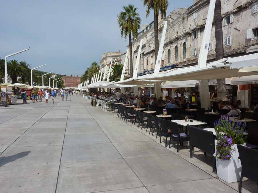 Terrasses de cafés et restaurants animés sur la Riva, le front de mer de Split bordé de palmiers en Croatie
