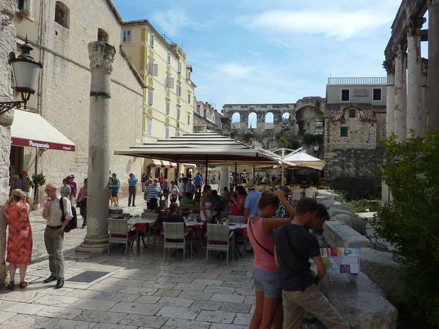 Terrasse de café dans le palais de Dioclétien à Split avec colonnes romaines et péristyle en arrière-plan
