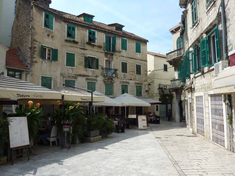 Terrasse de la Tavern Feral sur une placette pavée de la vieille ville de Split avec façades aux volets verts
