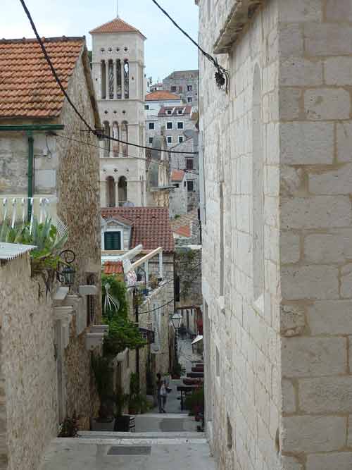 Ruelle pavée en escaliers de la vieille ville de Hvar sur le chemin de la forteresse Fortica, avec le campanile de la cathédrale en arrière-plan
