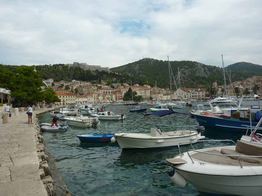 Le port de Hvar avec ses barques de pêche et la forteresse Fortica perchée sur la colline boisée en arrière-plan, Croatie