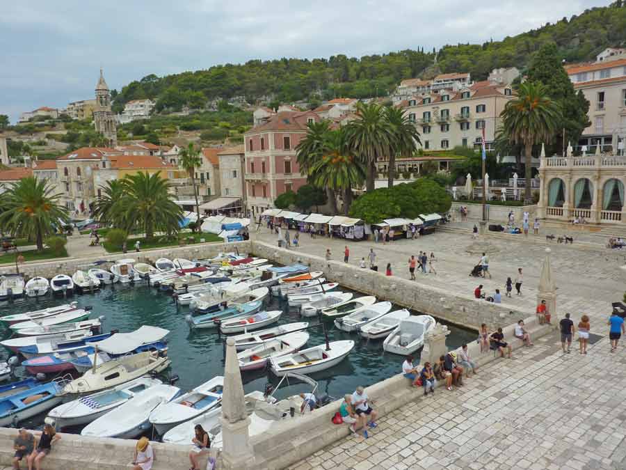 Le port de Hvar animé avec ses bateaux à moteur colorés, le marché local et les façades de la vieille ville dalmate