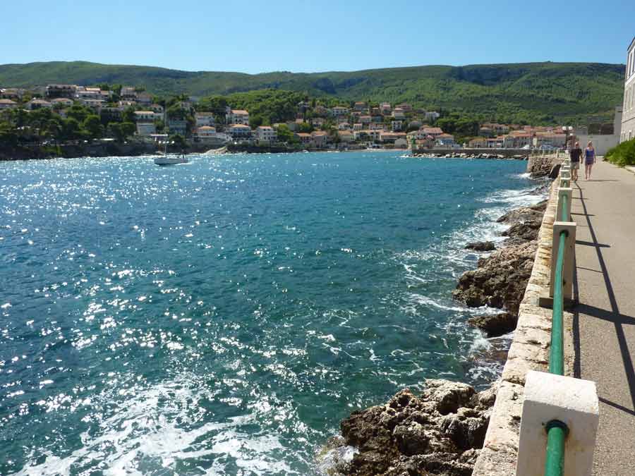 La jetée de Stari Grad longeant les eaux scintillantes de la mer Adriatique avec le village en arrière-plan, Hvar, Croatie