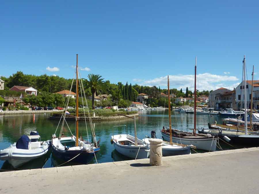 Port pittoresque de Stari Grad avec ses voiliers en bois traditionnels et ses maisons en pierre entourées de végétation, Hvar, Croatie
