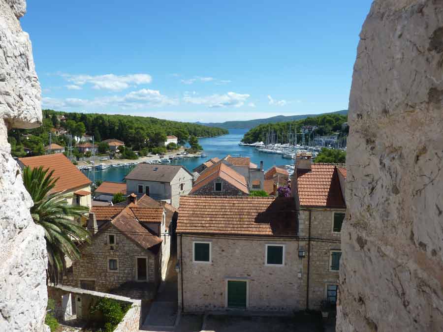 Vue depuis les hauteurs de Stari Grad sur les toits en tuiles, la baie et le port de plaisance encadré de collines boisées, Hvar, Croatie