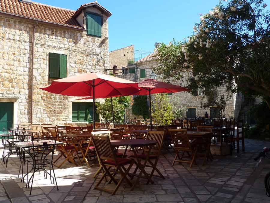 Tables et parasols rouges d'une konoba familiale dans la vieille ville de Stari Grad, Hvar