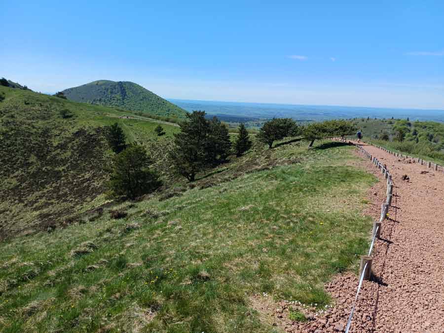 Chemin de terre sur la lèvre du cratère du puy Pariou avec vue sur les volcans voisins de la Chaîne des Puys