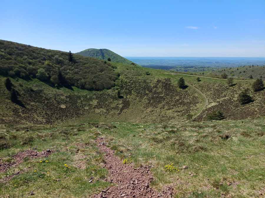 Cratère du puy Pariou vu depuis sa lèvre supérieure, avec ses parois de scories rougeâtres et le sentier longeant le rebord volcanique, Chaîne des Puys en Auvergne