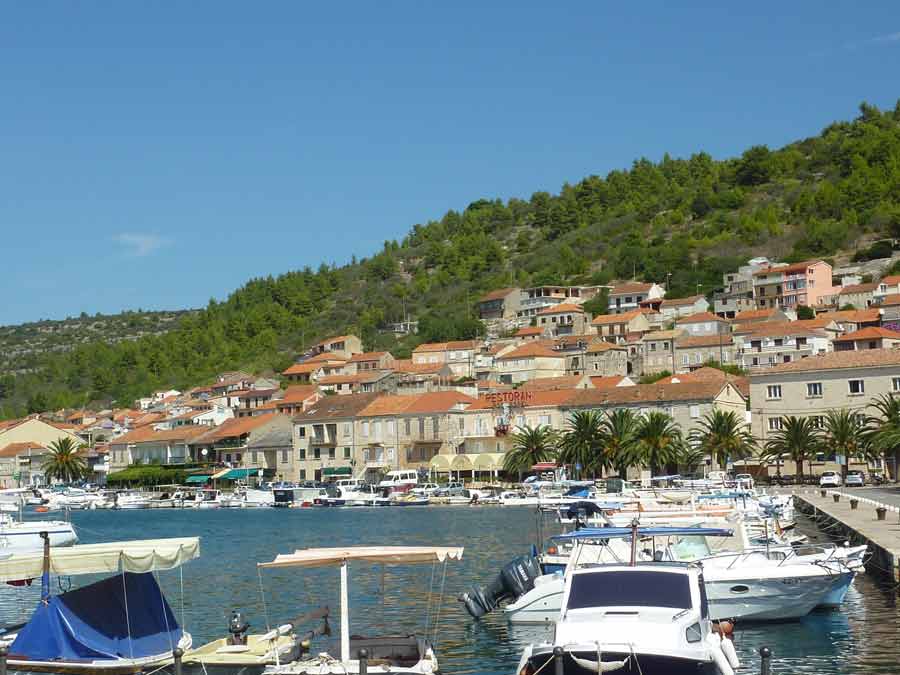 Port et village de Vela Luka à l'ouest de l'île de Korčula, avec ses maisons en pierre aux toits de tuiles orangées et ses bateaux amarrés