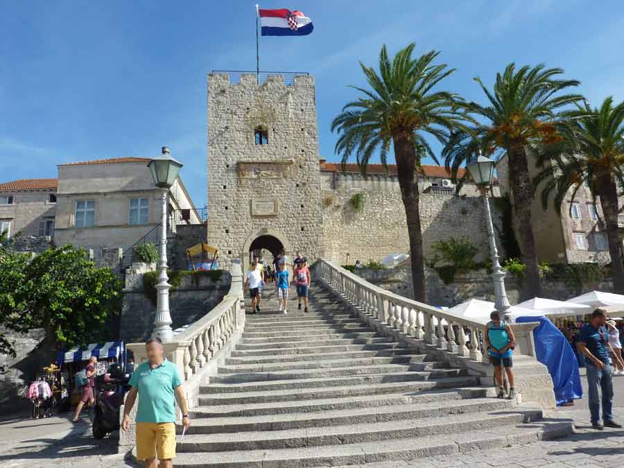 Porte principale et tour Revelin (tour à l'entrée de la vieille ville de Korčula) avec son grand escalier de pierre et le drapeau croate au sommet des remparts vénitiens