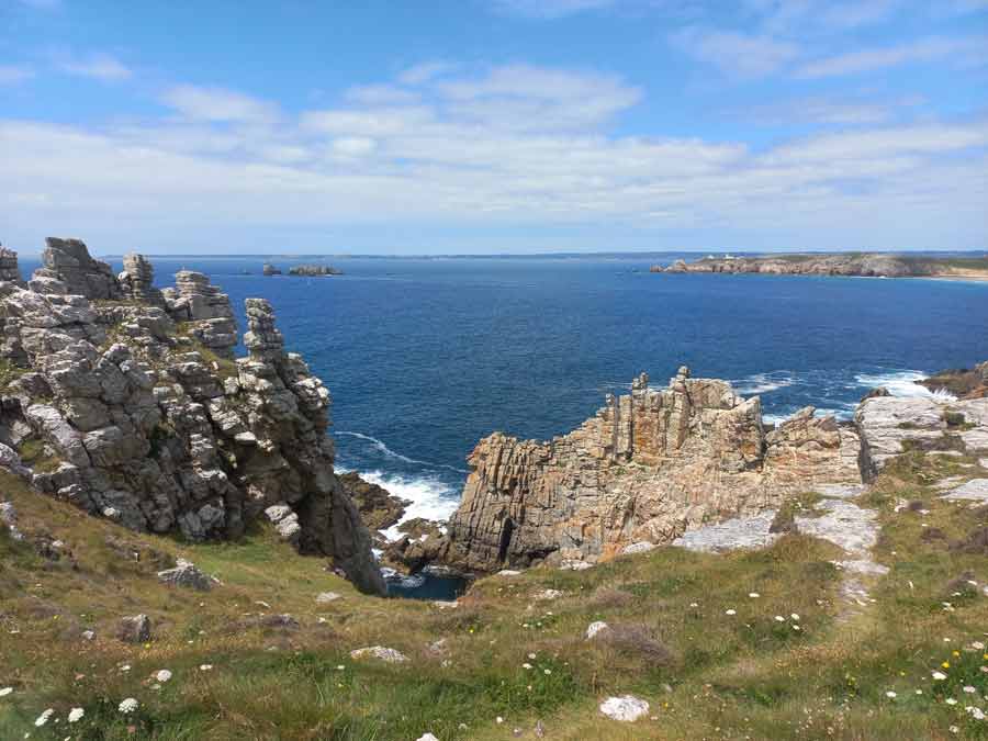 Formations rocheuses de grès armoricain en bord de falaise à la pointe de Pen Hir, avec vue sur l'Atlantique et la presqu'île de Crozon en arrière-plan, Finistère, Bretagne