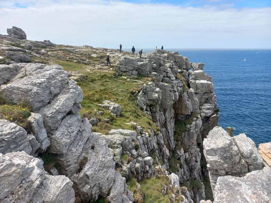 Visiteurs au bord des falaises de grès de la pointe de Pen Hir face à l'Atlantique, illustrant la verticalité du site et la prudence nécessaire en bord de vide, presqu'île de Crozon, Bretagne
