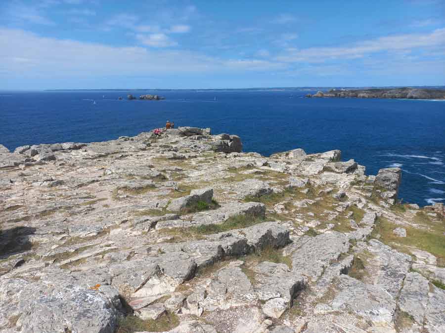Plateau rocheux de la pointe de Pen Hir avec des visiteurs contemplant l'Atlantique, les Tas de Pois et la presqu'île de Crozon en arrière-plan, Finistère, Bretagne
