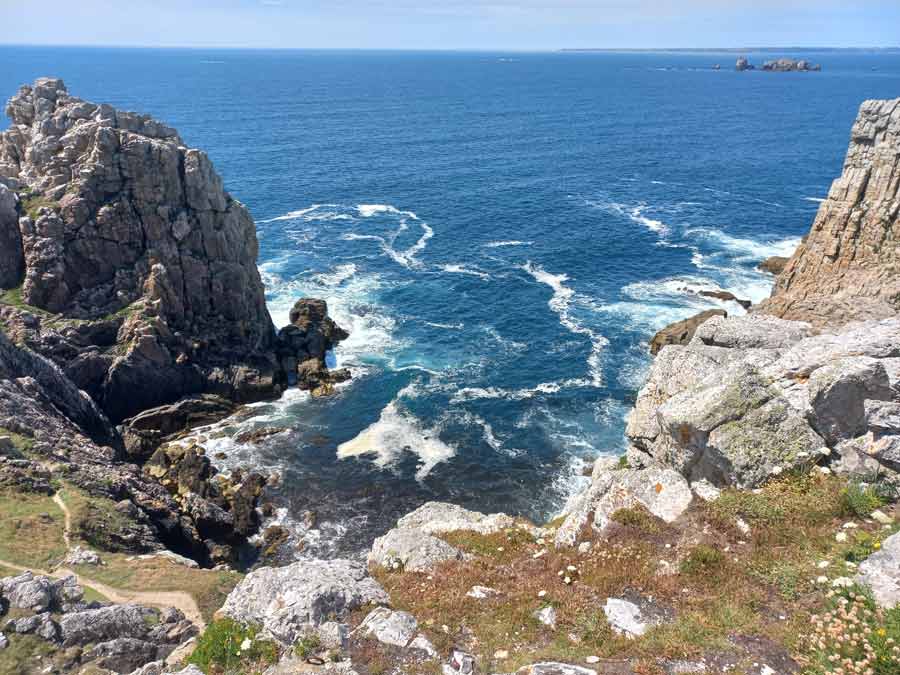 Vue plongeante sur les eaux turquoise et les rochers déchiquetés au pied des falaises de Pen Hir