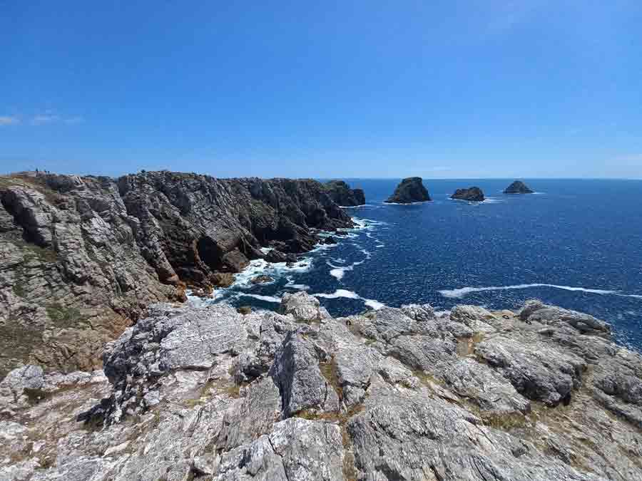 Falaises de grès armoricain de la pointe de Pen Hir plongeant dans l'Atlantique, avec les rochers des Tas de Pois au large sous un ciel bleu